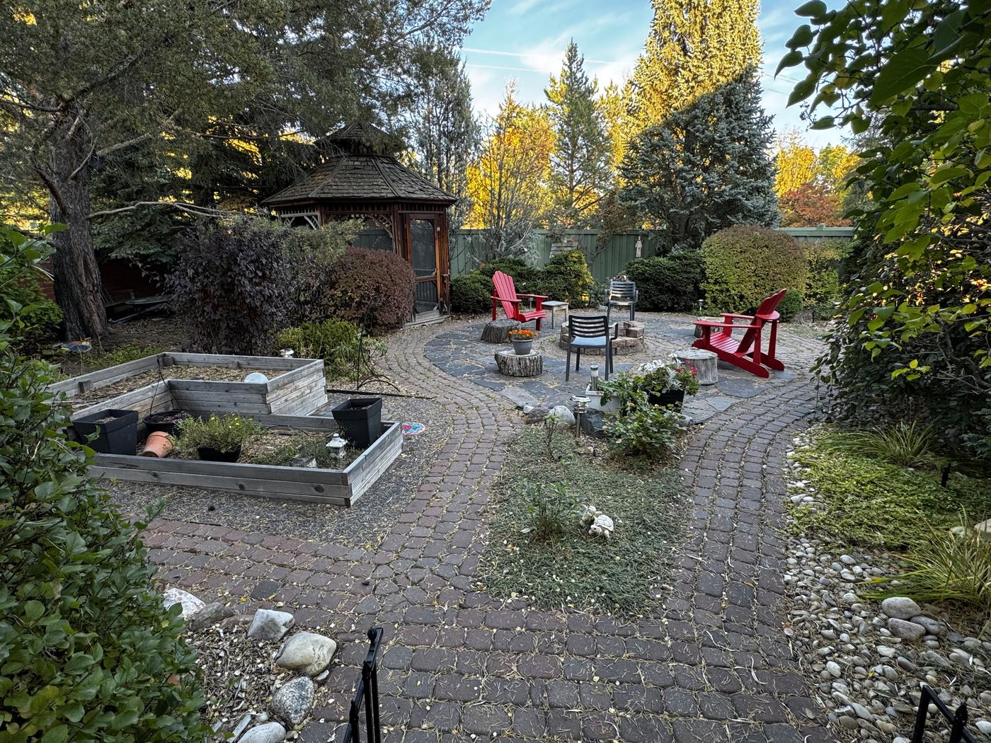 Raised garden beds and curved stone paths winding through planted borders in the back garden.
