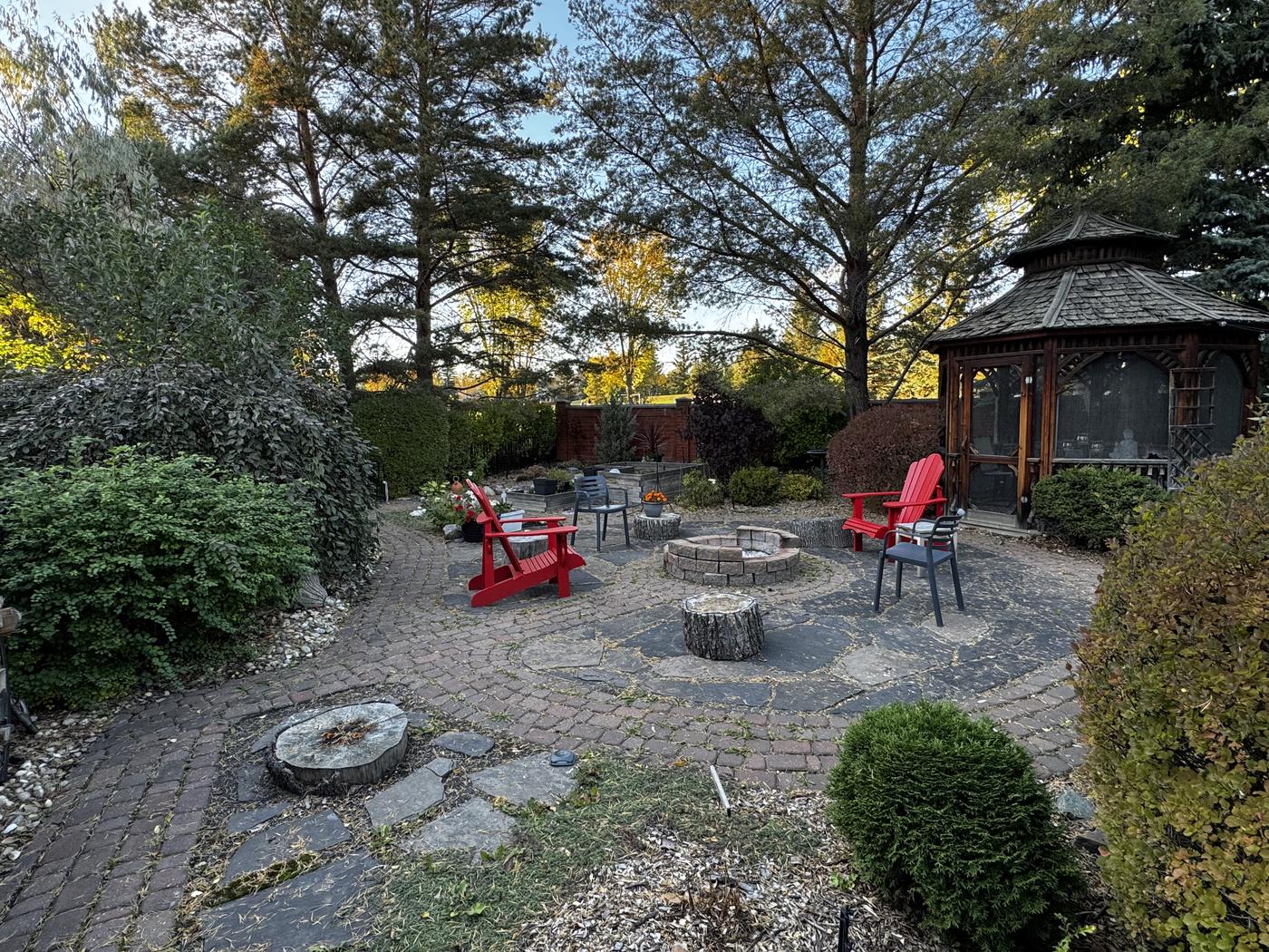 The screened wooden gazebo at the edge of the flagstone terrace, surrounded by mature planting.