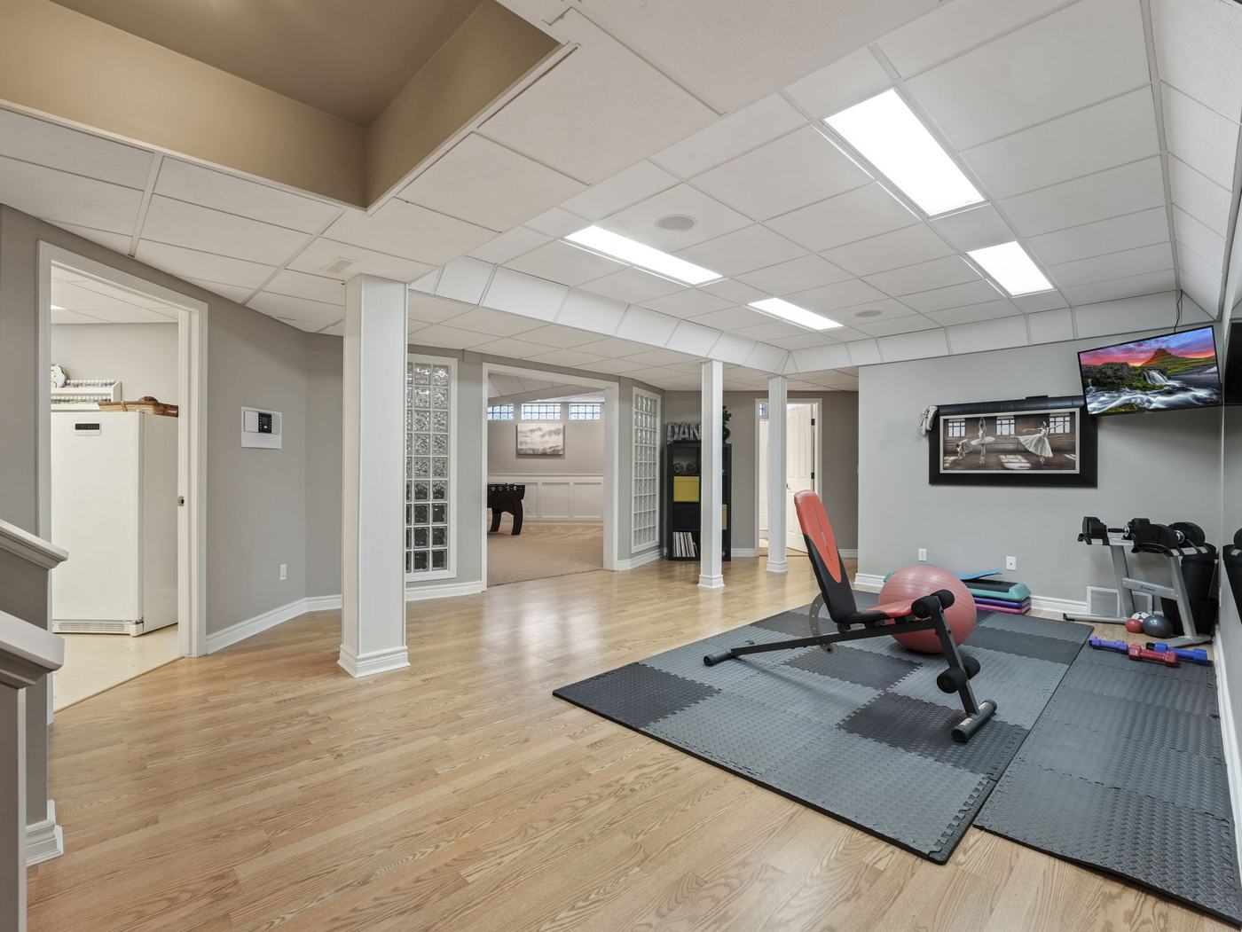 The lower level gym and dance studio with a mirrored wall and hardwood floor.