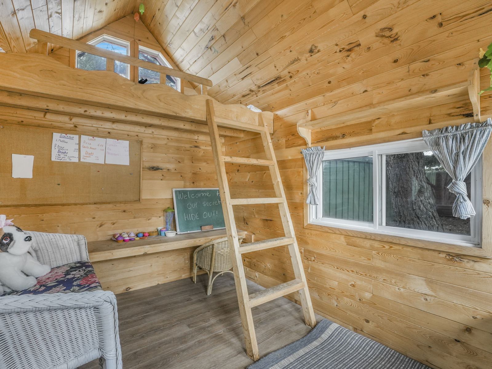 Inside the cedar-lined playhouse in the back garden, with a chalkboard, a window seat and a ladder up to its own loft.