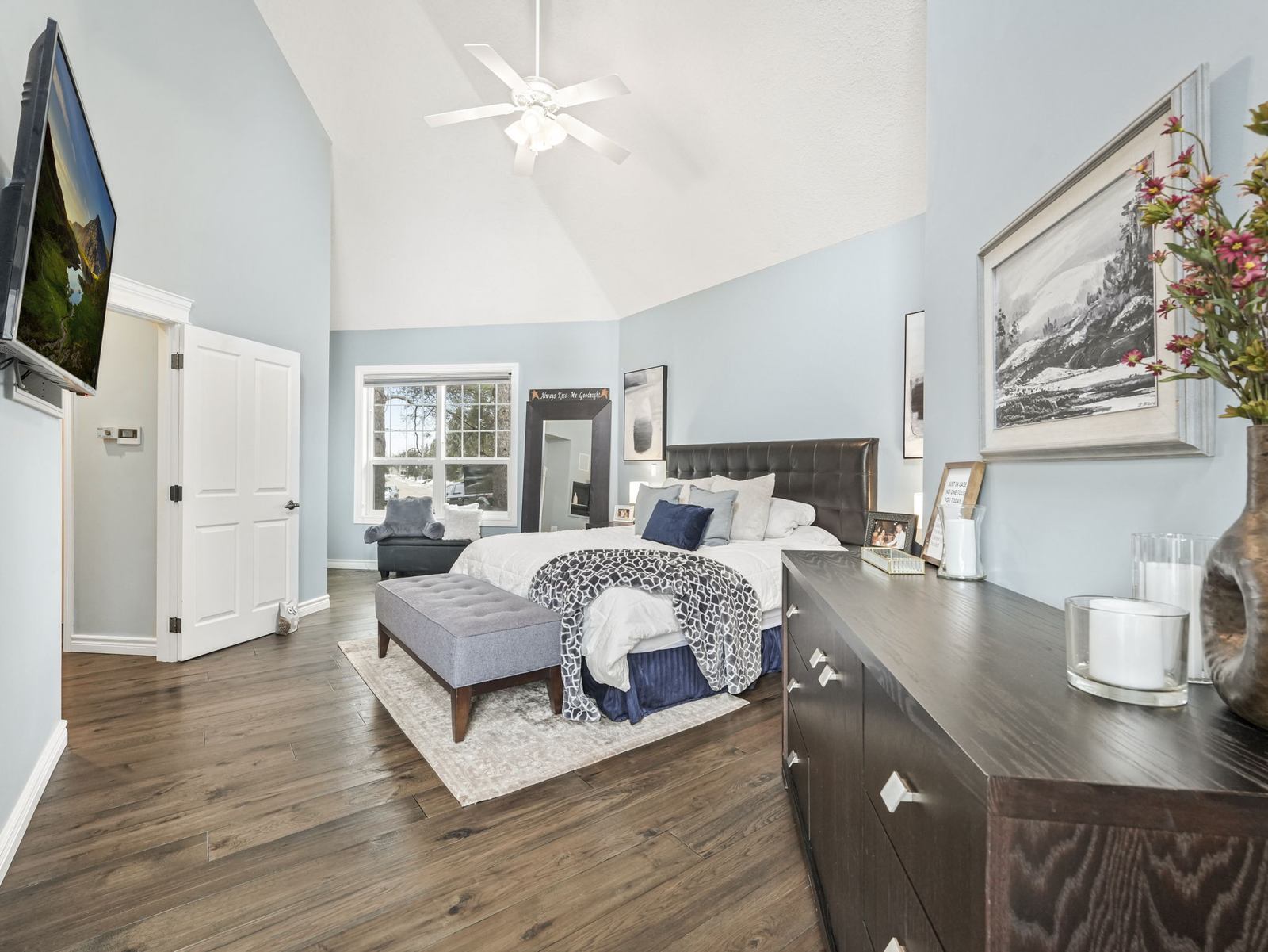The main floor primary bedroom under a vaulted ceiling, with a door through to the ensuite.
