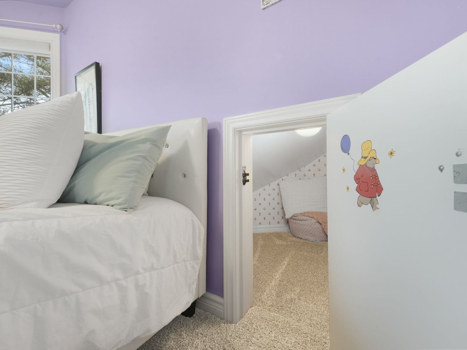 A small child-height door standing open in an upper bedroom, showing the hidden room behind it.