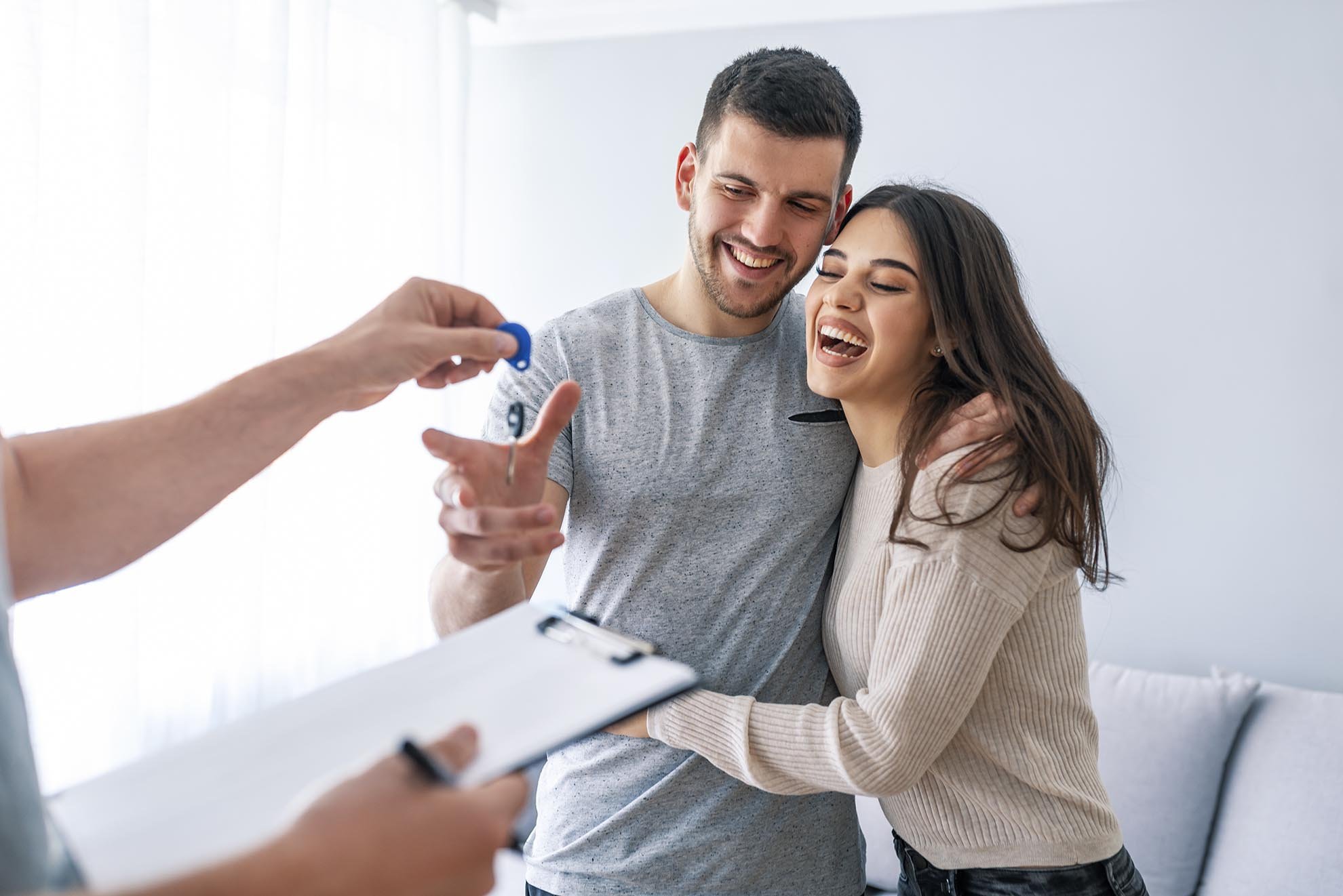 Happy couple is taking keys from their new house from broker and