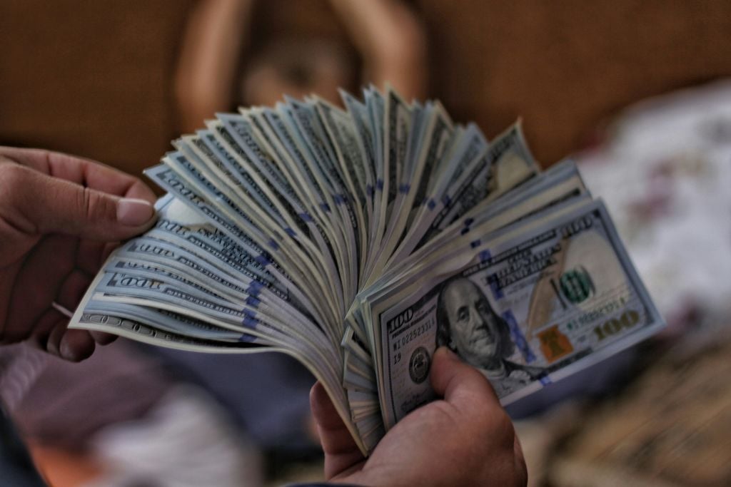 Hands holding a stack of 100 dollar bills