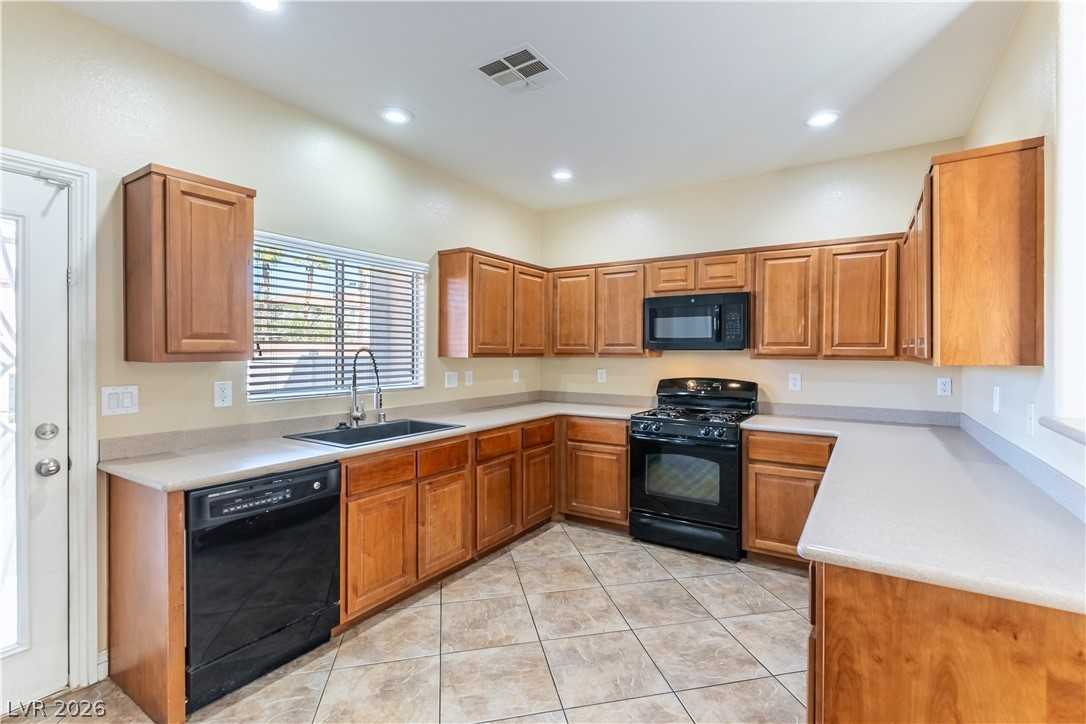 Kitchen with wood cabinetry and black appliances at 9010 Mossy Hollow Avenue
