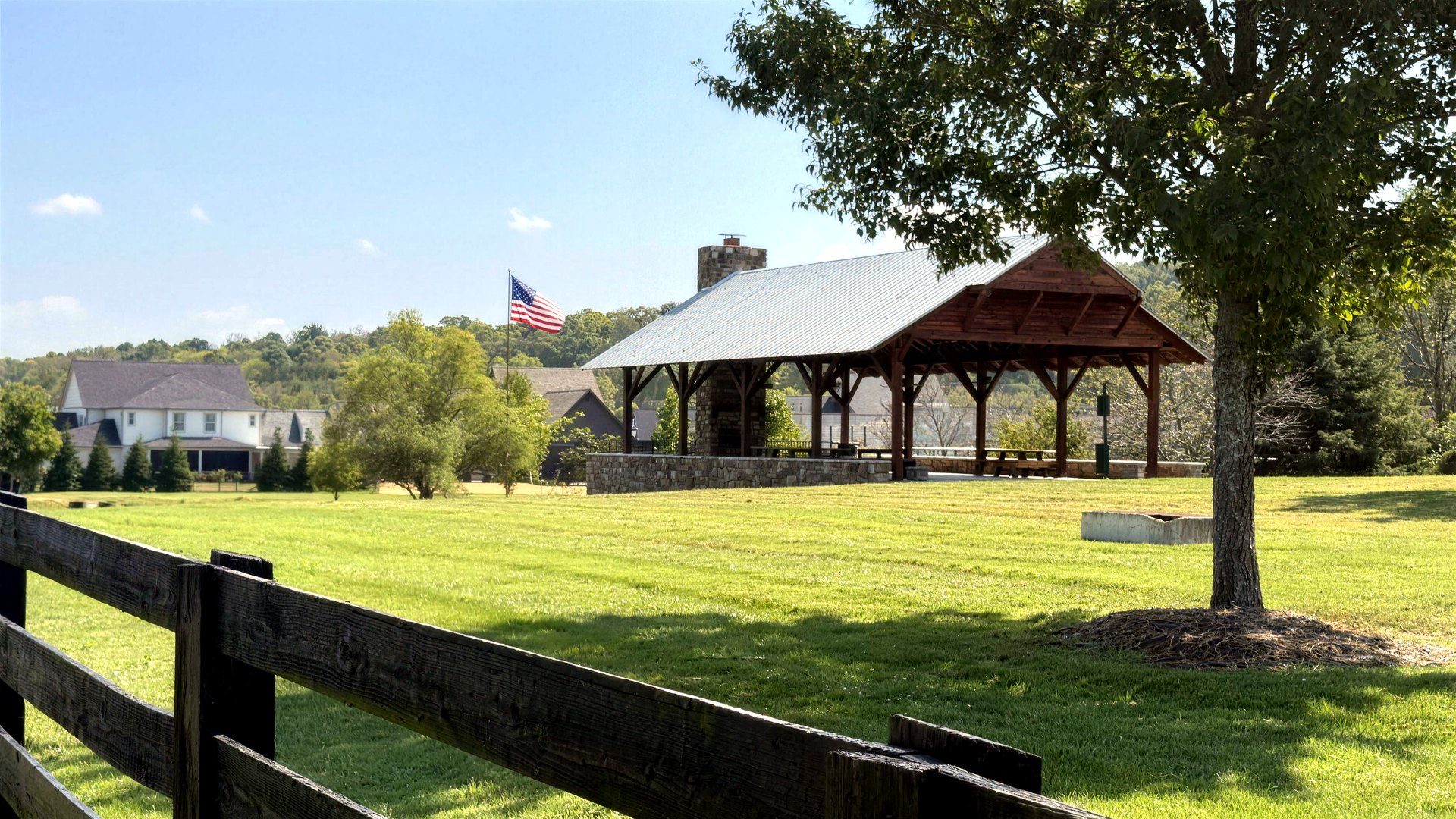 Timber pavilion and flag on a lawn behind a black horse fence in College Grove, Tennessee