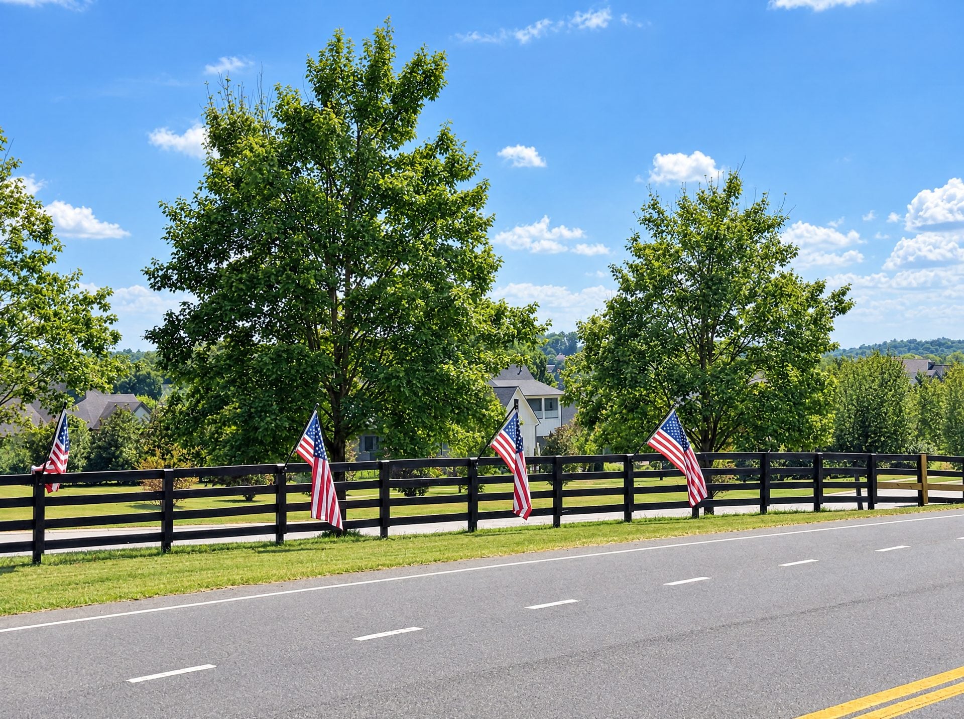 Black four-board fence lined with American flags along a road in College Grove, TN
