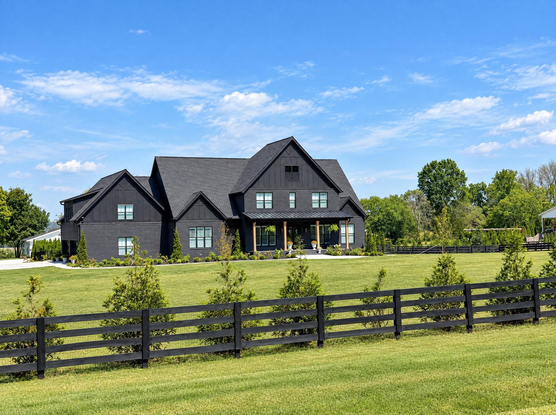 Modern black farmhouse behind a four-board fence in College Grove, TN