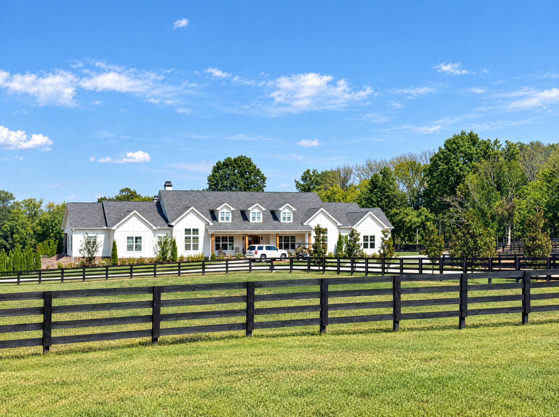White farmhouse with a wide front porch on a pasture in College Grove, TN