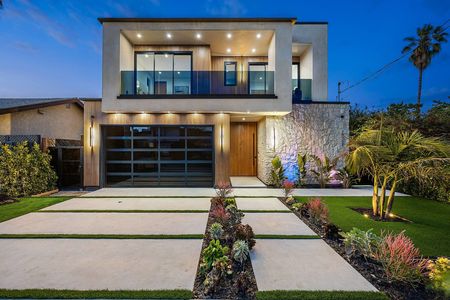 Modern two-story house with a well-lit exterior and landscaped front yard featuring palm trees and succulents