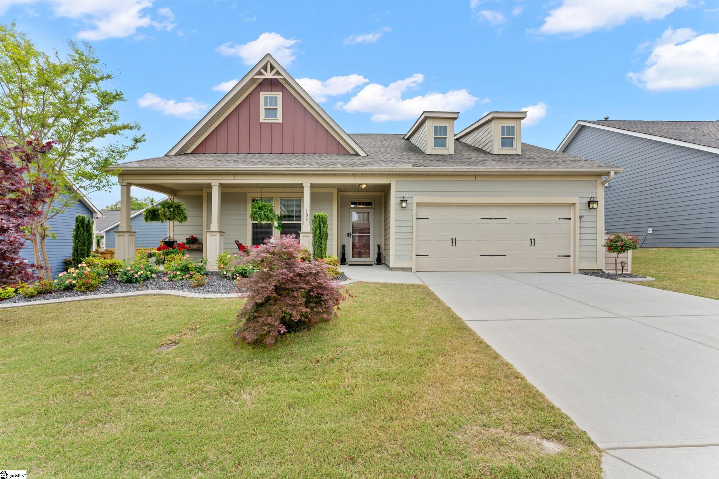 Front view of a well-maintained 3-bedroom home in Taylors, SC with a covered front porch, landscaped yard, and two-car garage