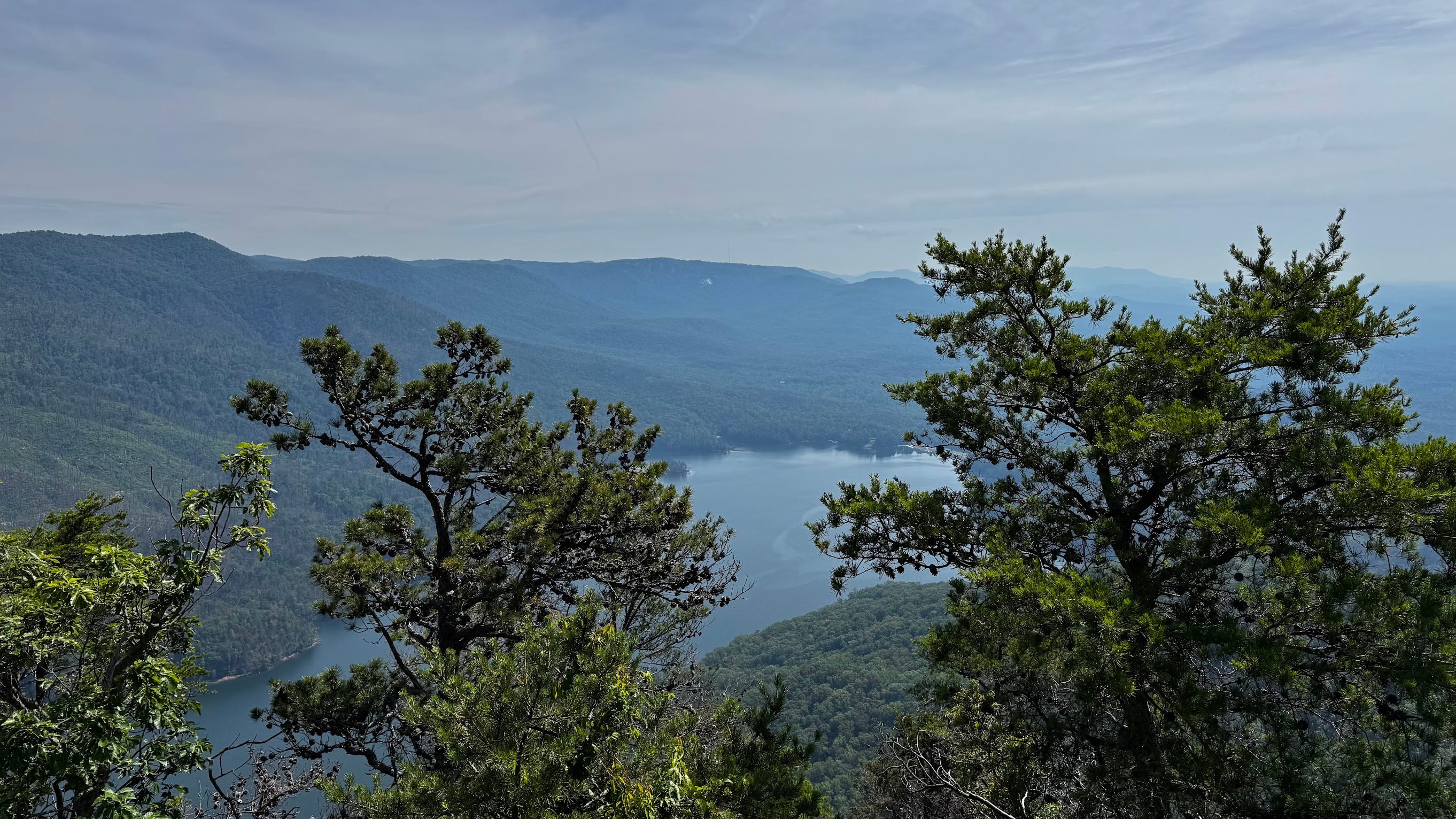Scenic mountain view from Table Rock Trail overlooking the lake, rolling Blue Ridge Mountains, and pine trees in South Carolina.