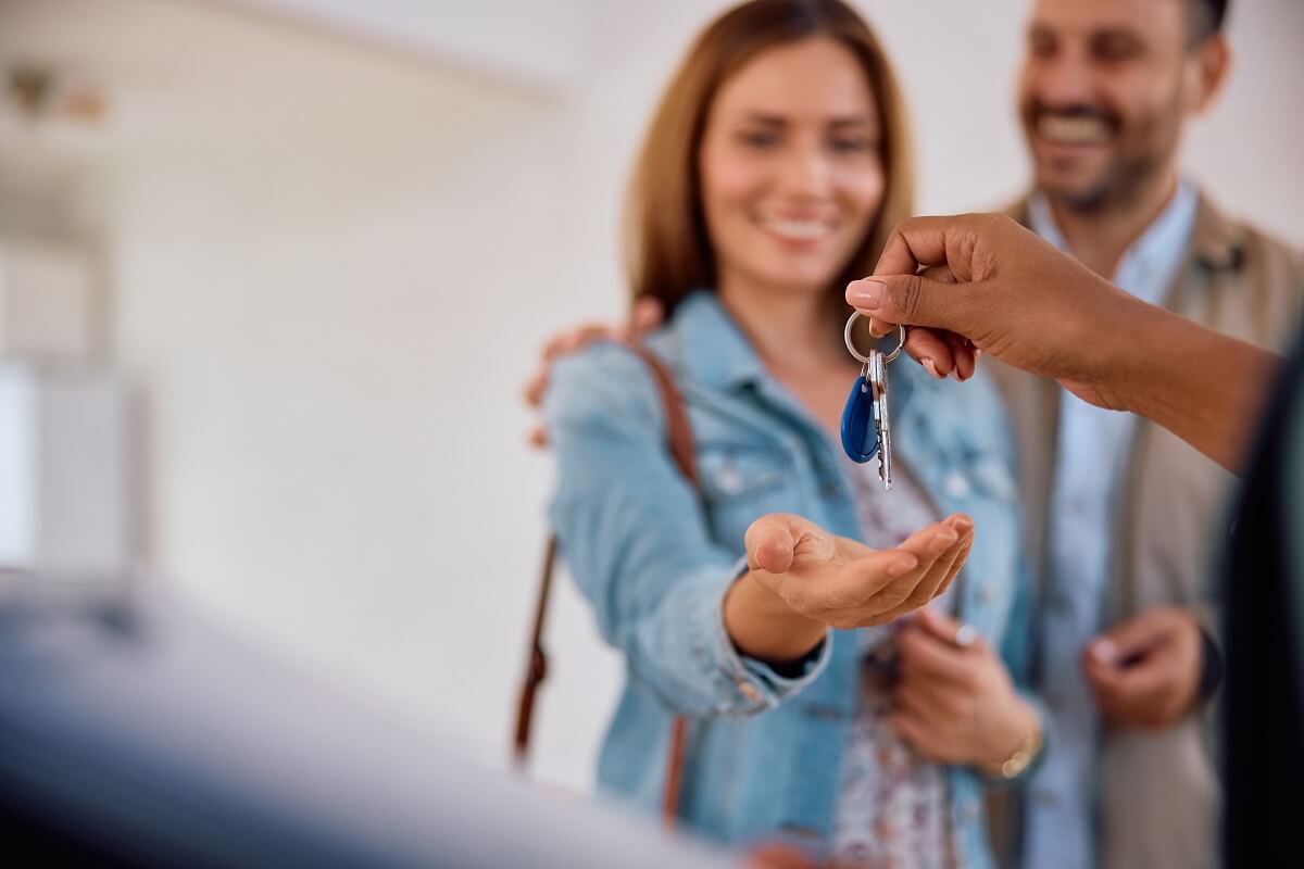 Close up of real estate agent giving new house keys to a couple