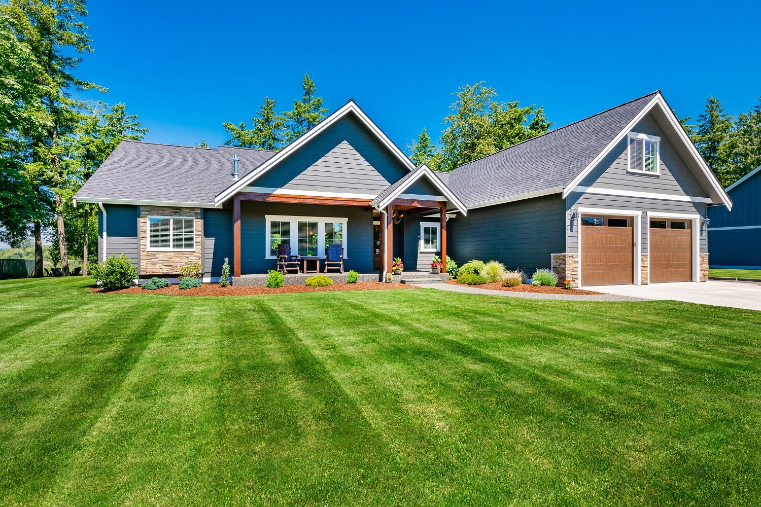 Craftsman home with double garage lush green lawn and blue sky