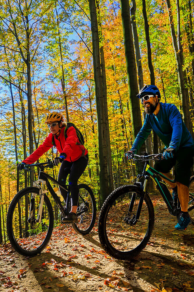 Cycling-woman-and-man-riding-on-bikes-at-sunset