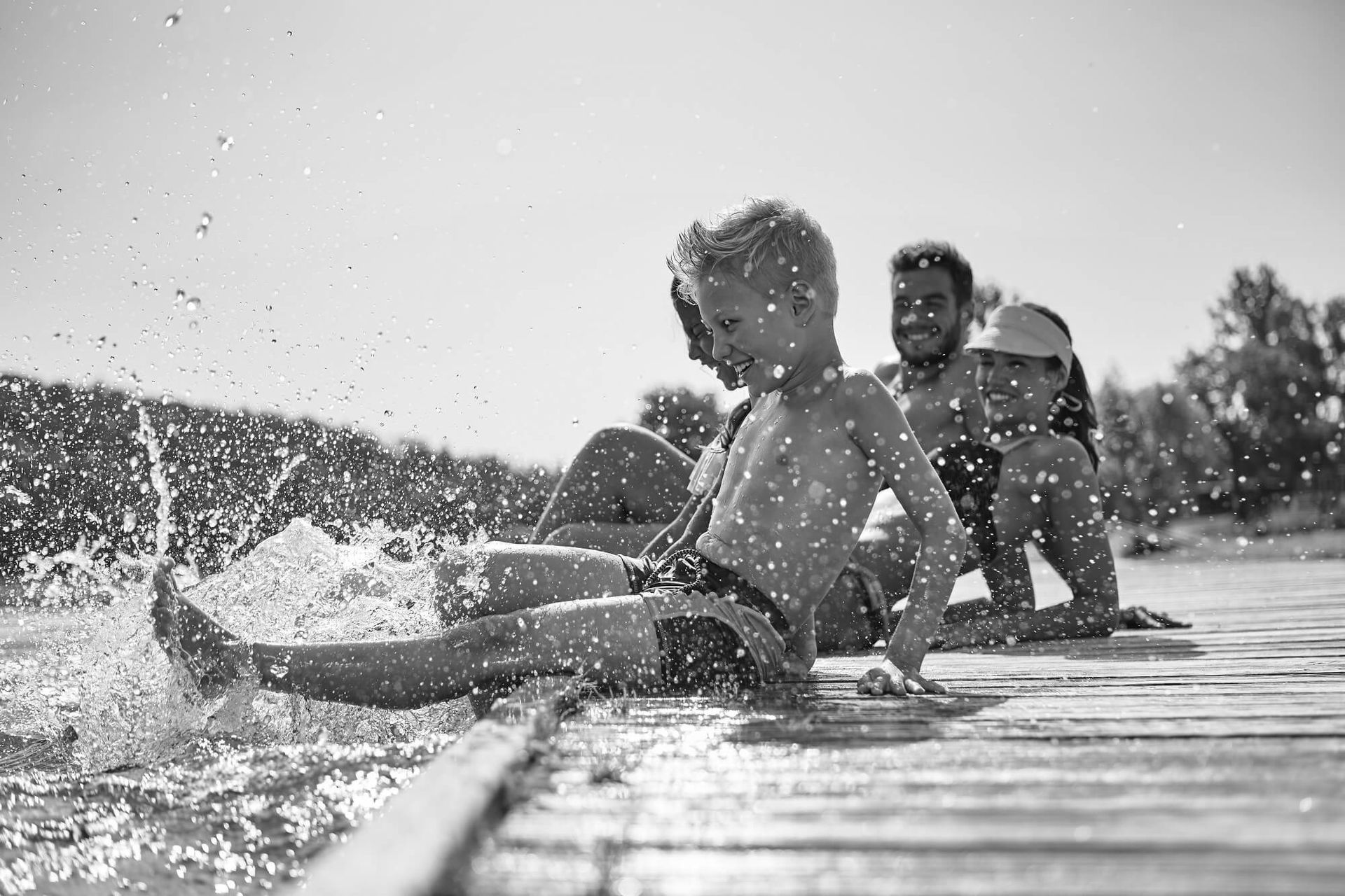 Happy family at a lake having fun and splashing water in summer