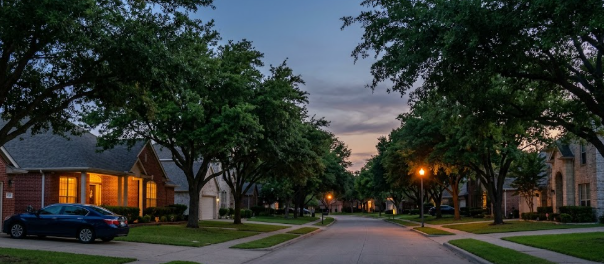 Quiet tree-lined Keller TX neighborhood street at dusk with no traffic