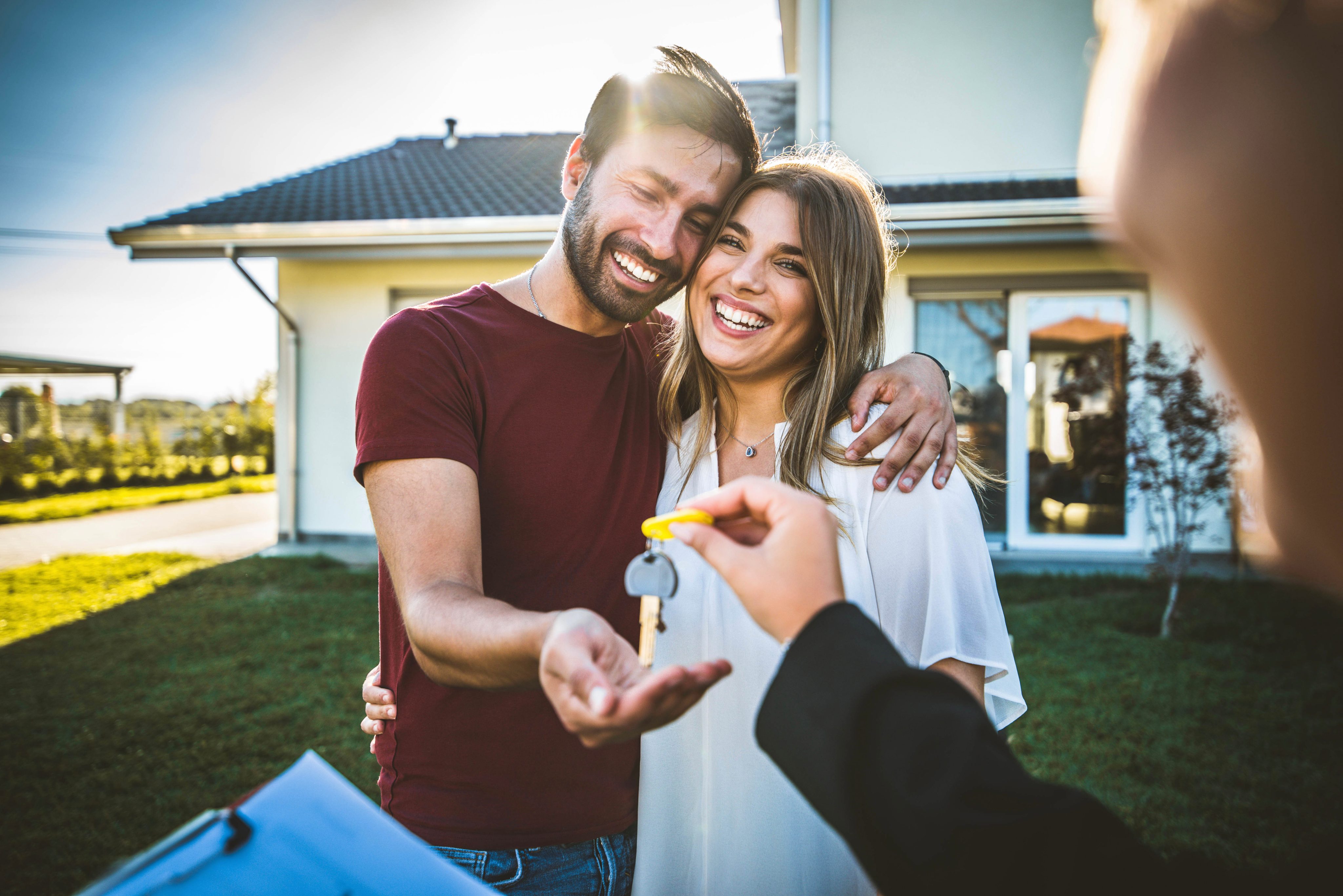 Happy millennial couple receiving keys from realtor, purchasing
