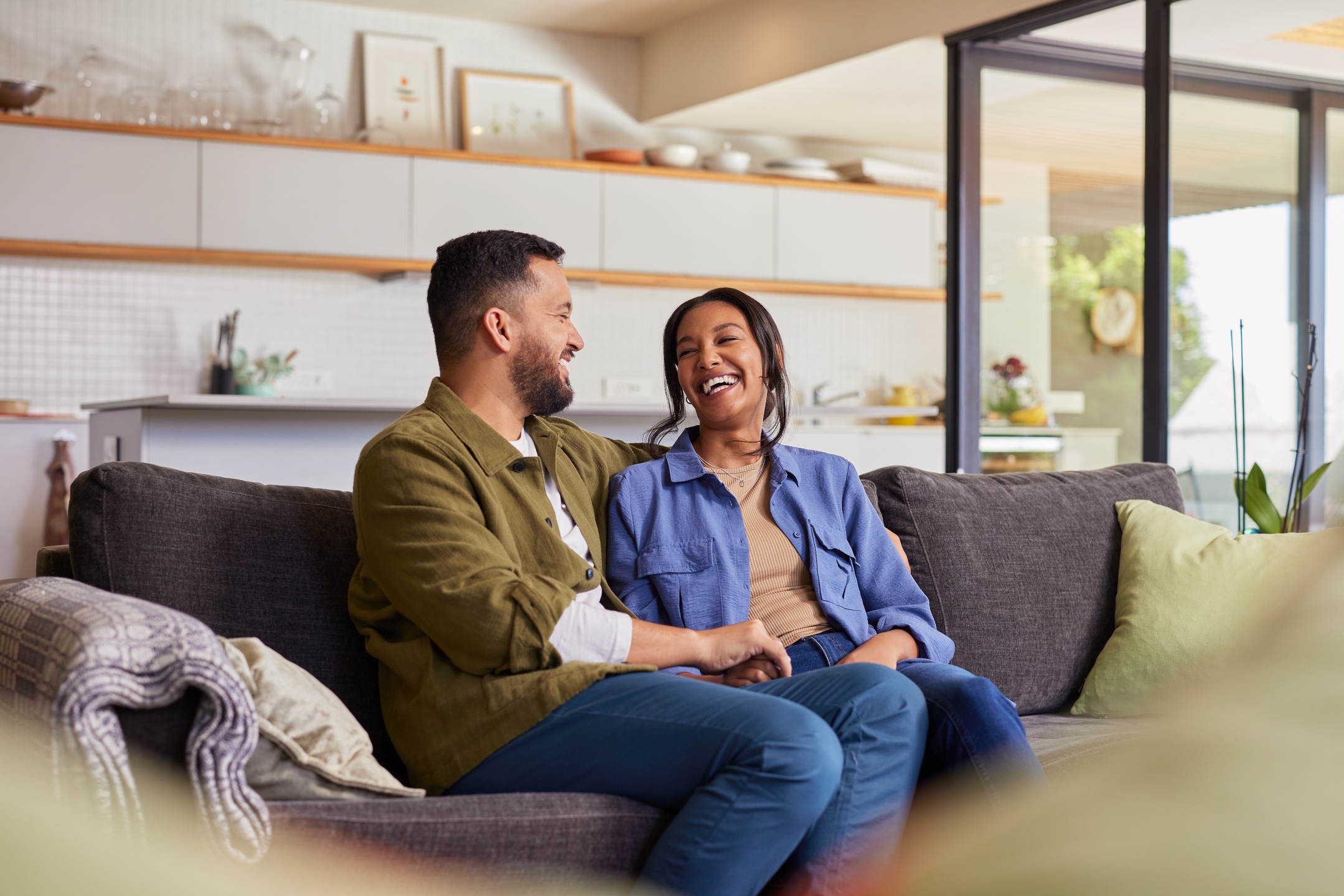 Happy,Positive,Indian,Couple,Sitting,On,Couch,Laughing,And,Spending