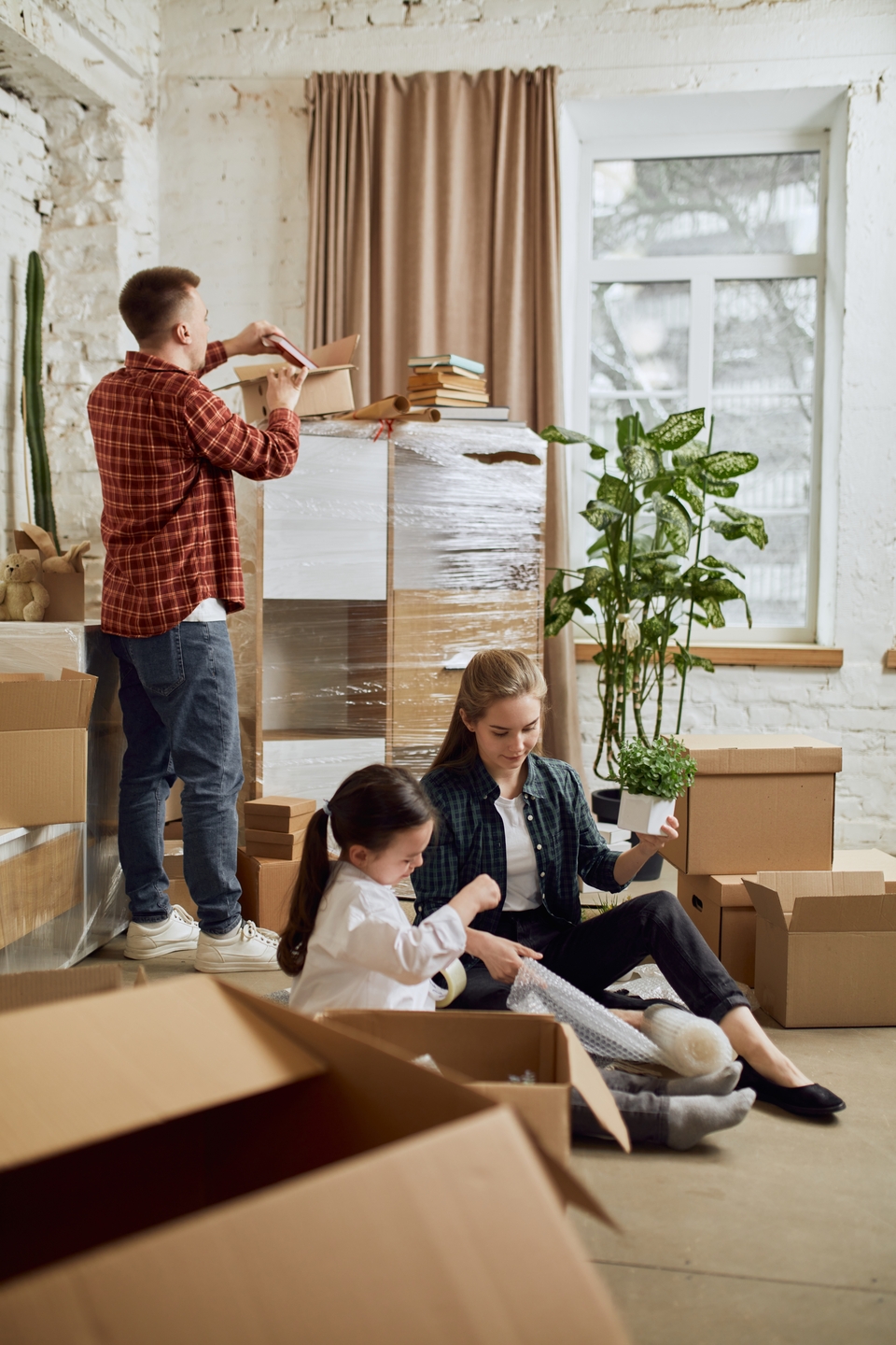 Young,Happy,Family,,Man,,Woman,And,Kid,Moving,Into,New