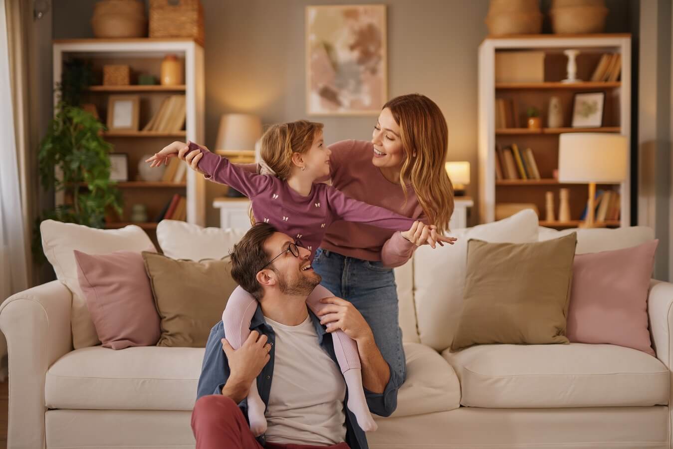 Mom, dad and little daughter playing flying game in the living room