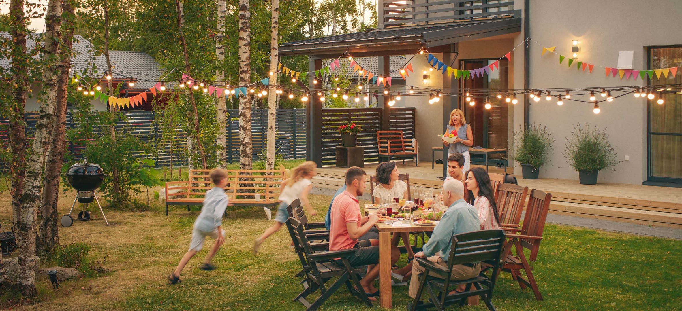 Big-Family-Garden-Party-Celebration,-Gathered-Together-at-the-Table-Family,-Friends-and-Children.-People-are-Drinking,-Passing-Dishes,-Joking-and-Having-Fun.-Kids-Run-Around-Table.