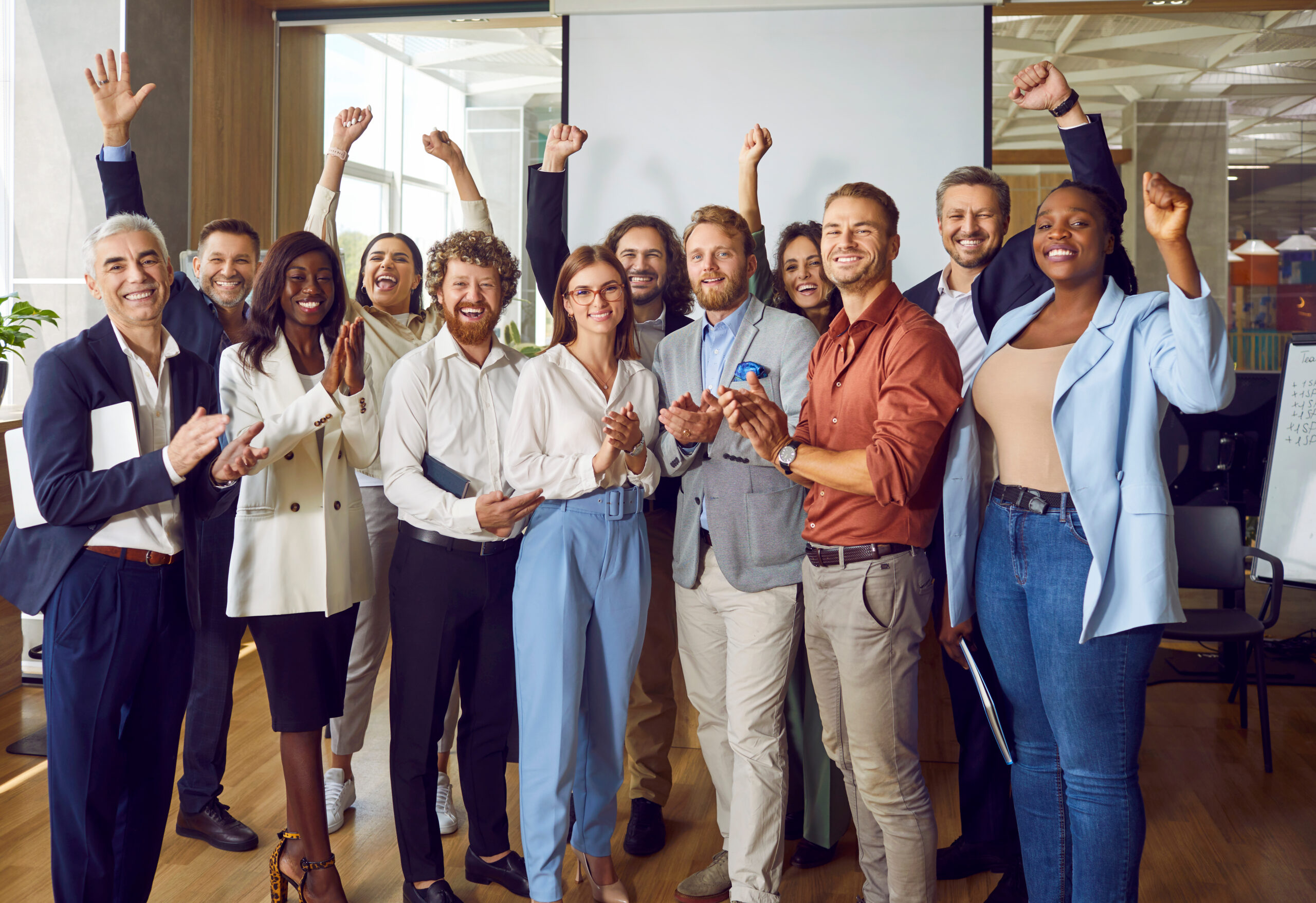Portrait of diverse happy business people standing in office and looking at the camera.