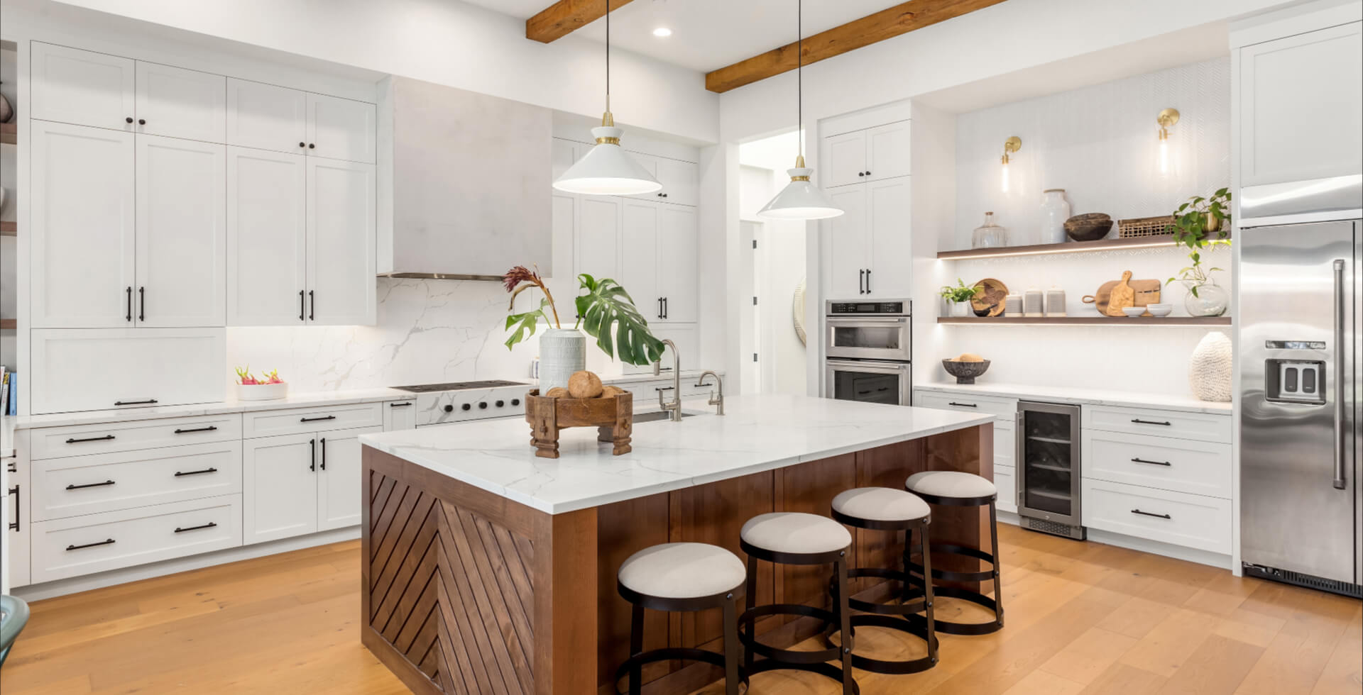 Beautiful white kitchen in new luxury home with large island. Features large island, stainless steel appliances, and sleek modern range hood.