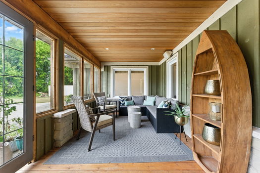 Covered porch area opening to the green yard.