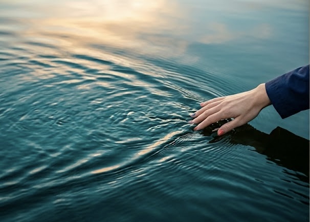 Hand touching river water representing lifestyle, timing, and decision making in Kemptville waterfront real estate