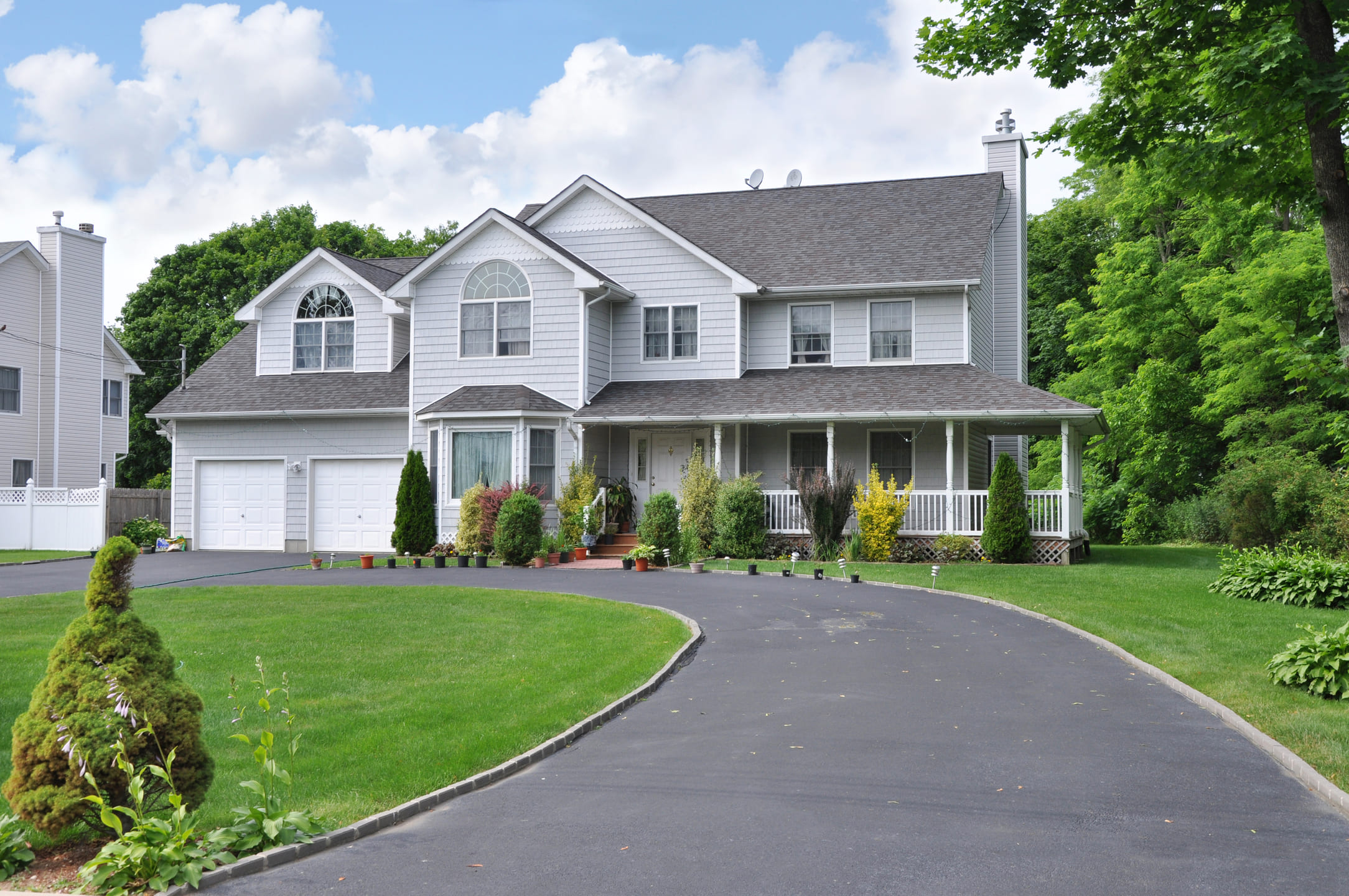 Large Suburban McMansion Home with blacktop circular driveway in residential neighborhood in USA