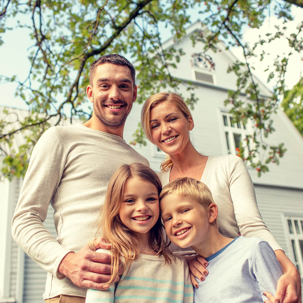 happy-family-standing-in-front-of-house-outdoors