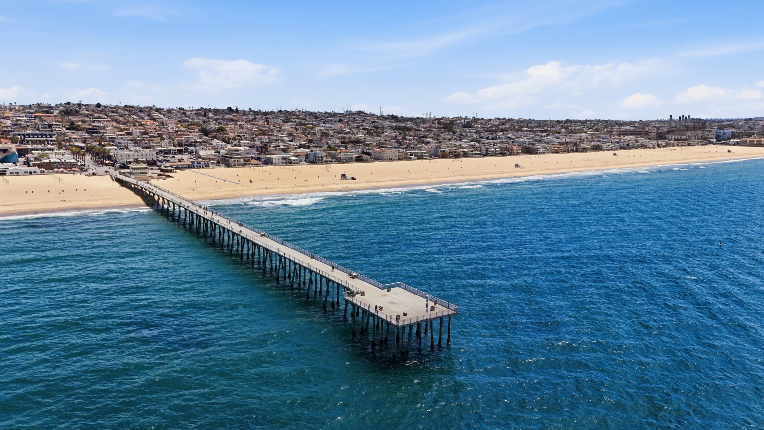 Drone aerial of Hermosa Beach Pier, beachfront homes, and the South Bay coastline in Southern California.