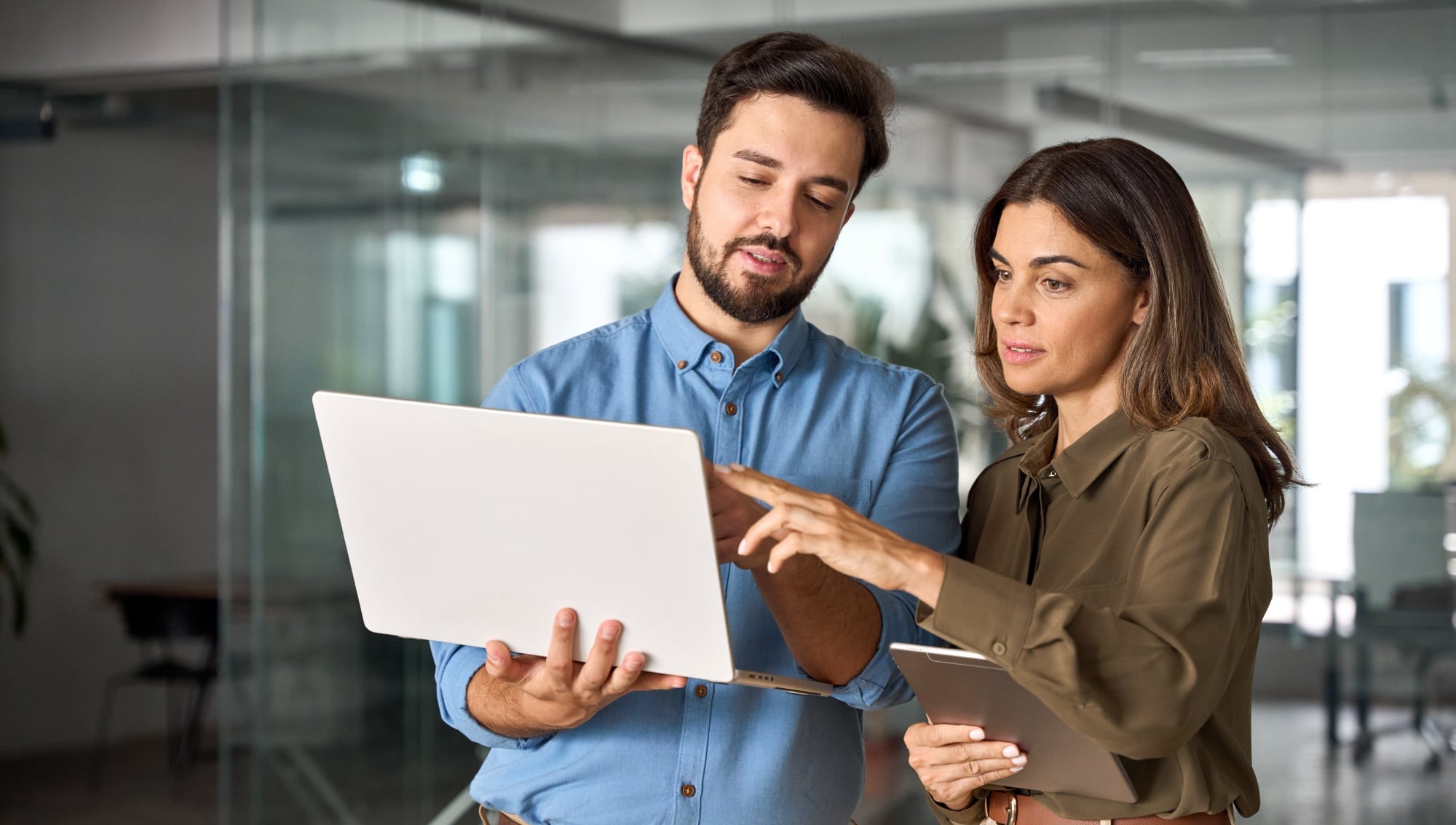 Two busy professional business people working in office with computer. Middle aged female executive manager talking to male colleague having conversation