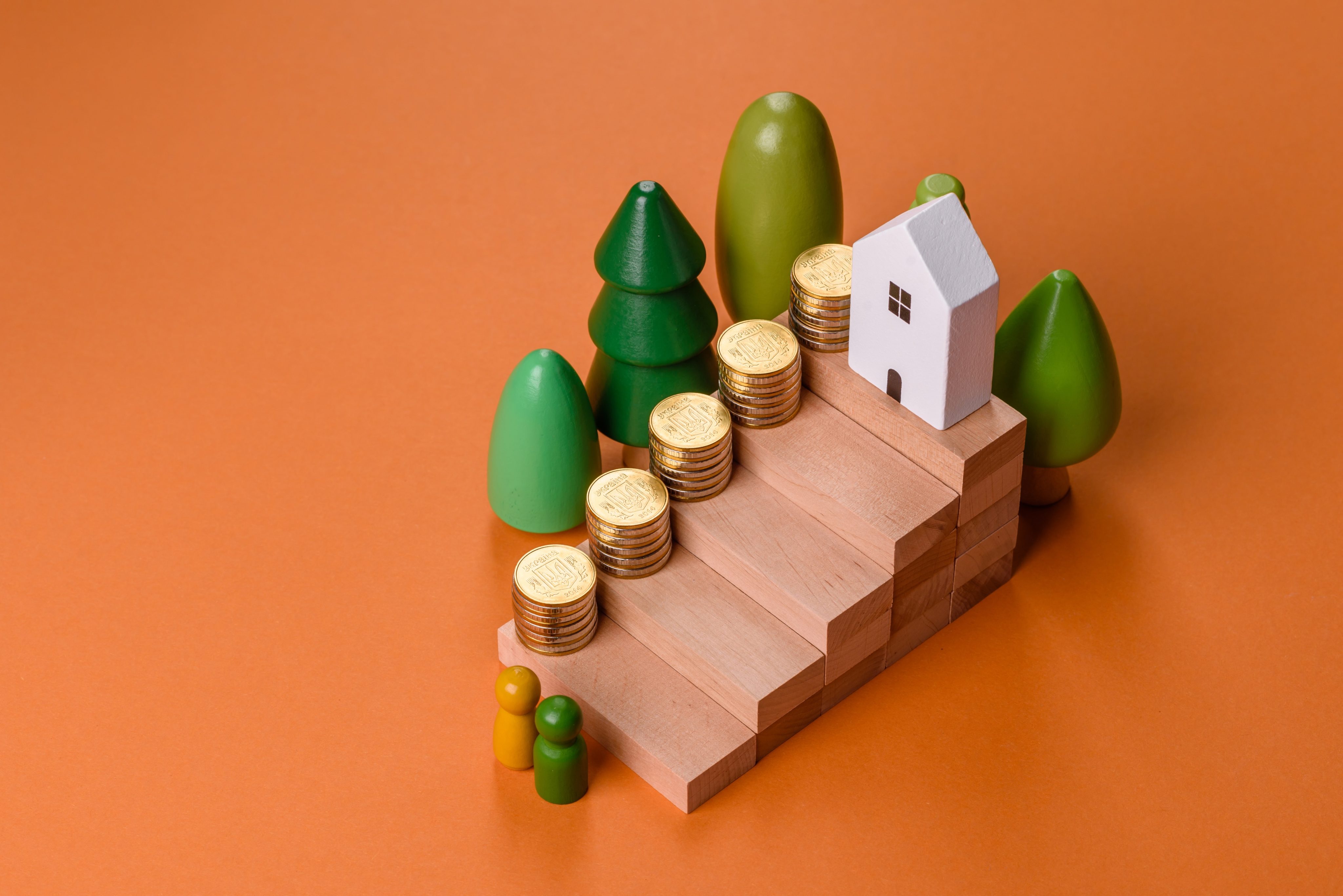 Conceptual composition of wooden steps with coins, model of a house
