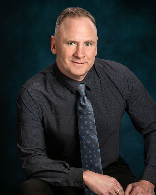 Realtor Tom Gilliam wearing a black shirt and tie