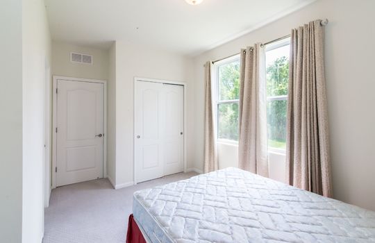 image shows a bedroom with a mattress on the floor, two white doors