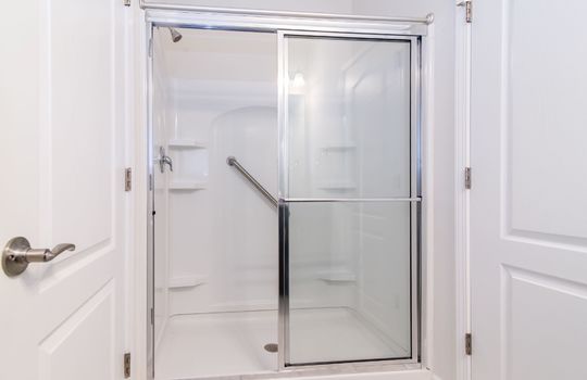 image displays a modern bathroom shower enclosure with a sliding glass door