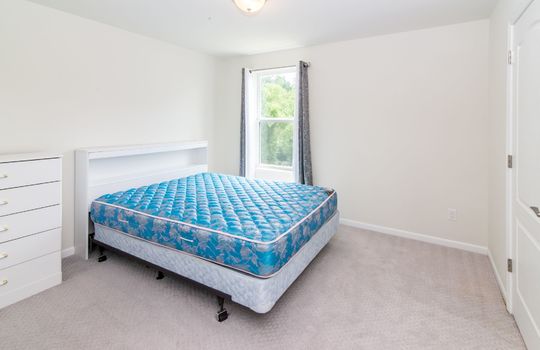 A bedroom with a bed, a dresser, and a window.