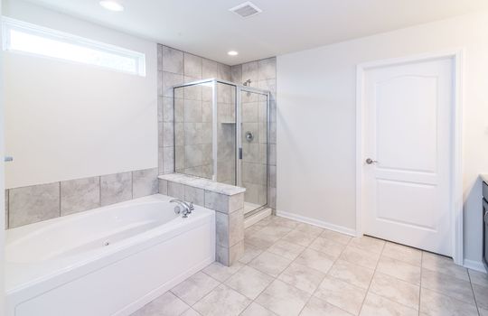 This image shows a bathroom with a bathtub, a separate shower stall, and a tiled floor