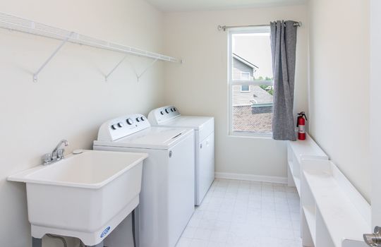 The image shows a laundry room with a washer, dryer, utility sink, and a window