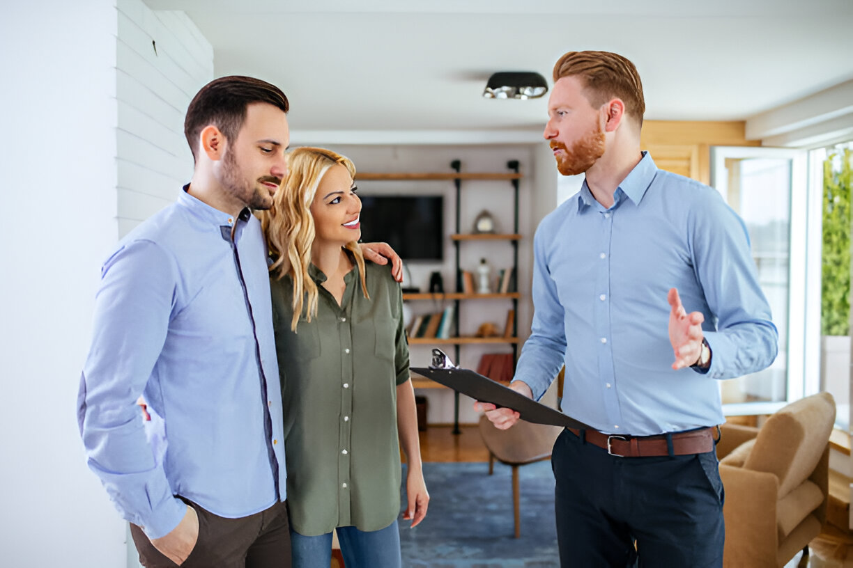 image shows three people inside a home, likely a couple and a real estate agent or a home-related professional