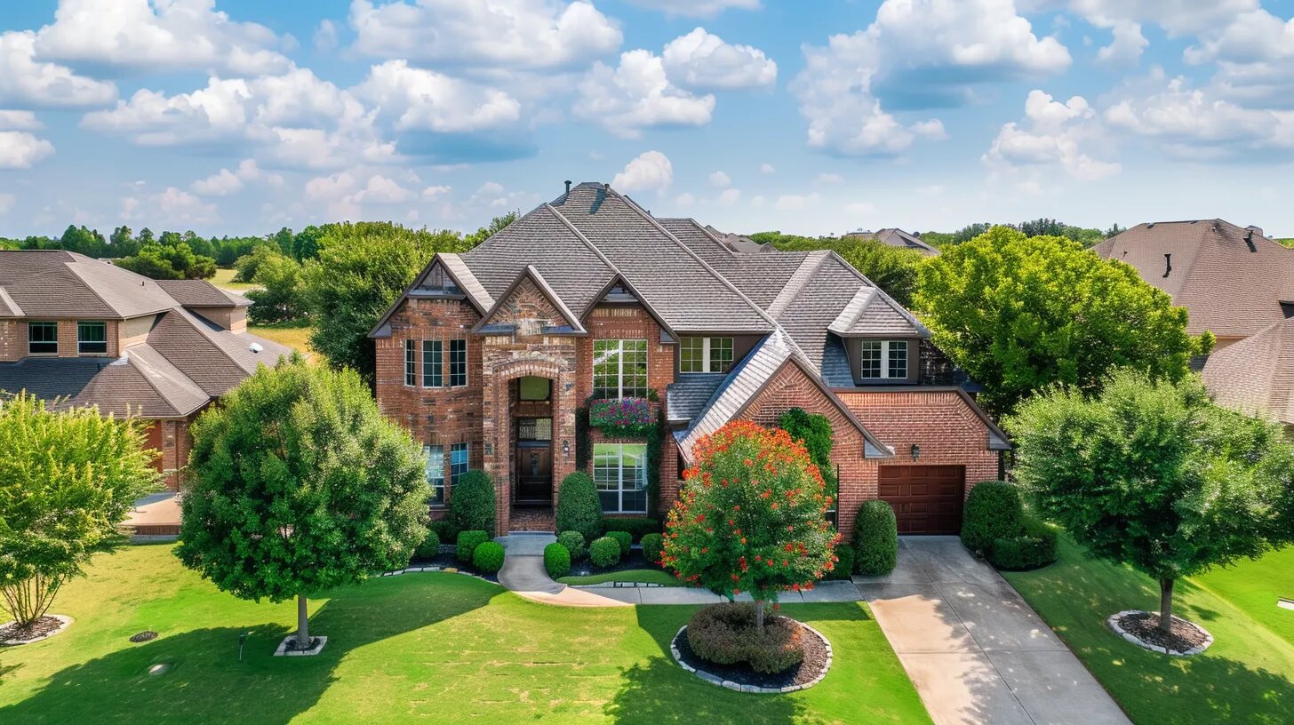 image shows a house is a large, two-story structure with a complex roofline, brick and stone facade, and a well-manicured lawn