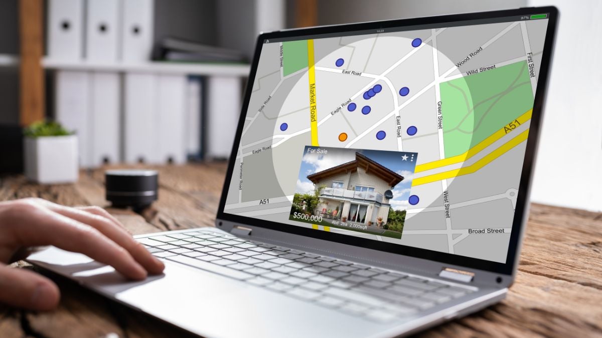 Person browsing Royal Oak Real Estate listings on a laptop with an interactive map, property details, and a featured home.