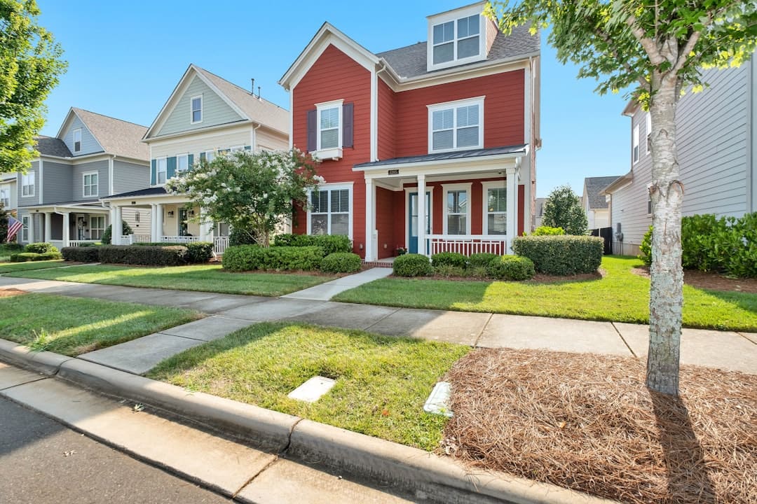Charming red colonial-style home with manicured landscaping and front porch in Farmington Hills, Michigan — an example of curb appeal improvements that increase property value