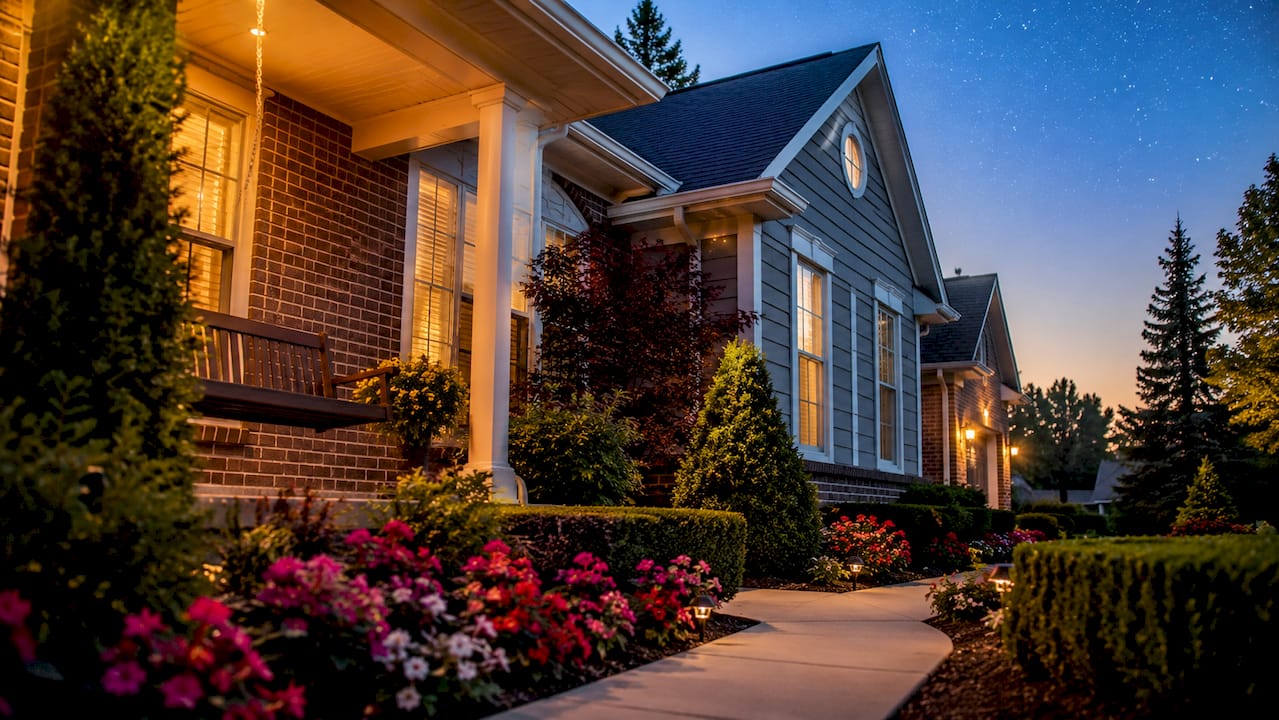 Well-maintained home exterior at dusk in an Oakland County Michigan neighborhood with landscaped garden