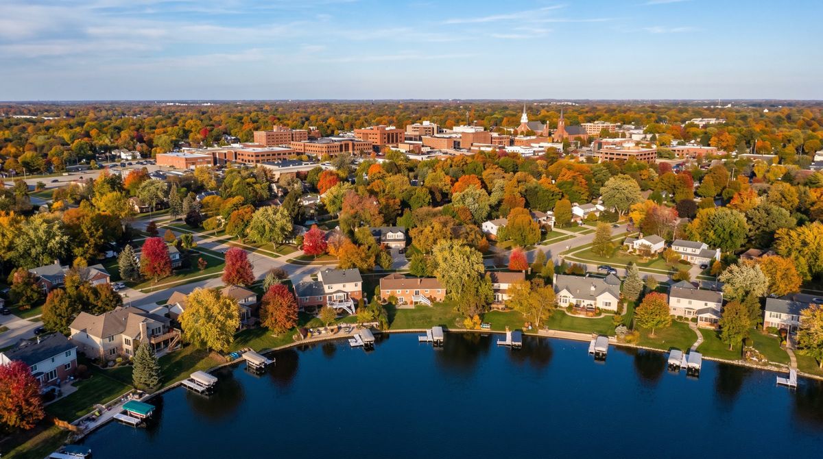 Aerial view of Oakland County, Michigan with lakefront homes and docks, suburban neighborhoods and a small downtown in fall