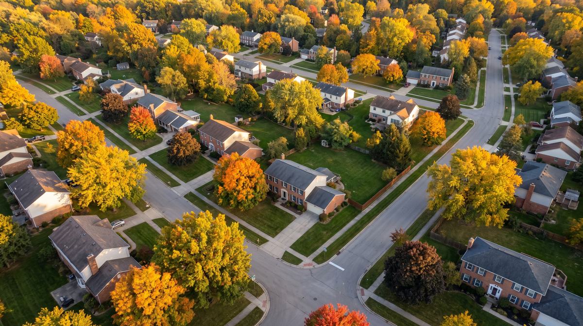 Aerial view of tree-lined residential streets and brick colonial homes in Farmington Hills, Michigan in early autumn