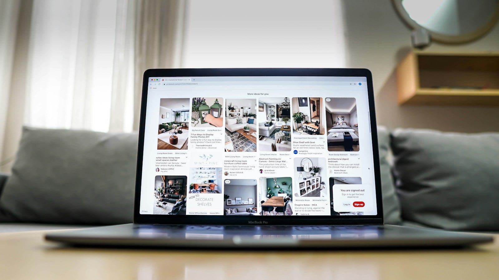 Laptop on a table in front of a sofa, its screen filled with dozens of home and room photos