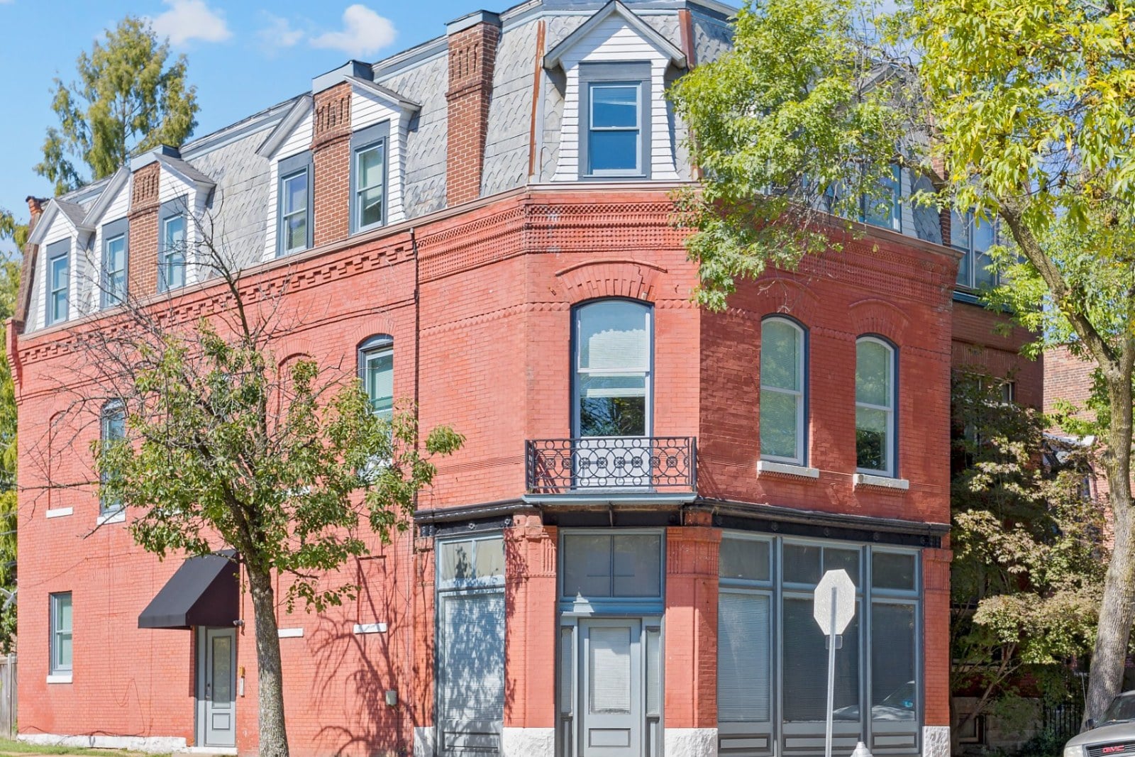 Historic red brick corner building in St. Louis with a slate mansard roof, dormer windows and a corner storefront
